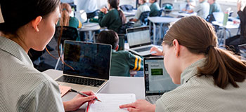 Two students sitting at desk discussing school work.