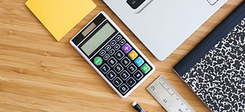 Calculator, laptop, pencil and ruler on desk.